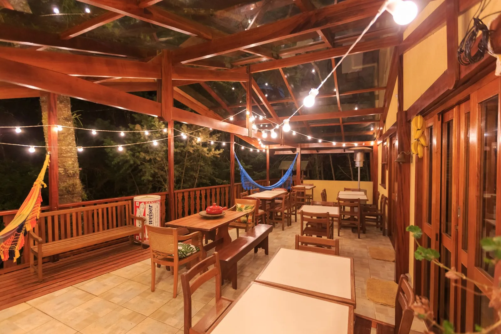 covered deck ideas — a pergola-covered wooden deck with string lights and outdoor seating